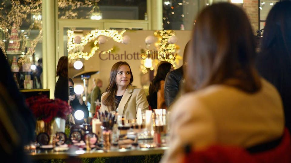 A woman sitting in front of the Charlotte Tilbury in-store Magic Mirror.