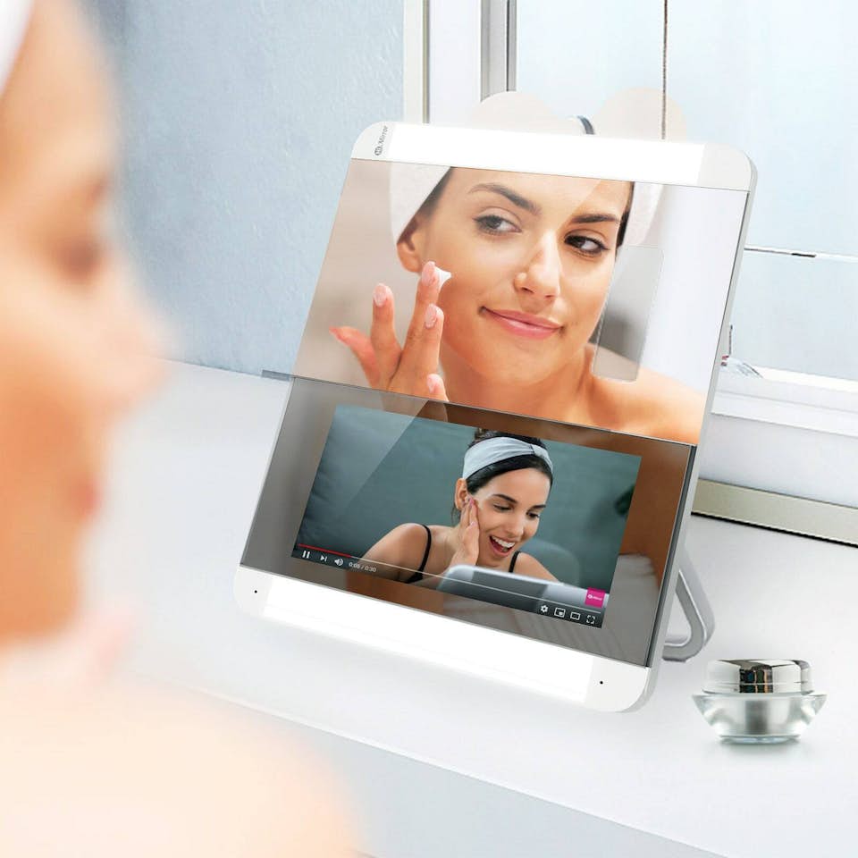 A smart mirror with a woman adjusting settings on the screen.