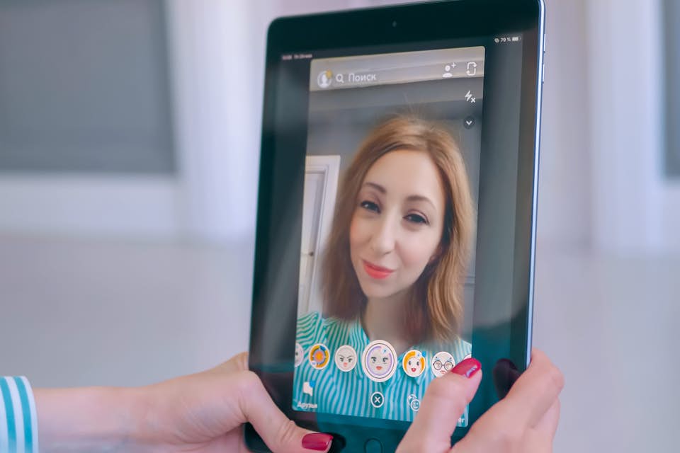 A young woman testing snapchat filters on her tablet device.